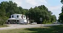 Gas station in two-story building beside highway running through woods