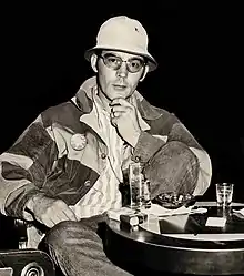 Portrait photograph of a 33-year-old man wearing a denim jacket, a bucket hat, and sunglasses