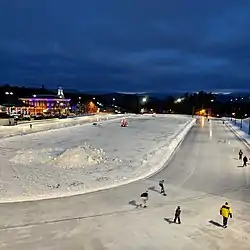 Outdoor nighttime photo of an illuminated oval with speed skaters