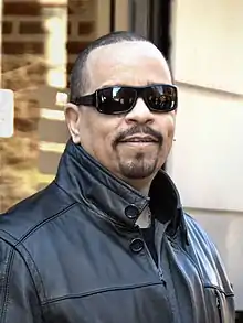 A man with a Van Dyke-style beard (goatee and mustache, shaved cheeks) wearing sunglasses and a leather jacket