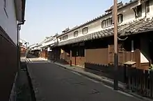 Wooden houses with a white upper storey lining a small street.