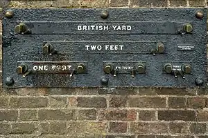 Imperial standard lengths on the wall of the Royal Observatory, Greenwich, London – 1 yard (3 feet), 2 feet, 1 foot, 6 inches (1/2-foot), and 3 inches. The separation of the inside faces of the marks is exact at an ambient temperature of 60 °F (16 °C) and a rod of the correct measure, resting on the pins, will fit snugly between them.