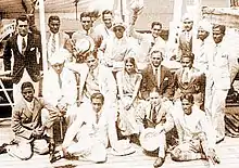 A group of Asian men wearing light coloured suits posing for the camera as a team.