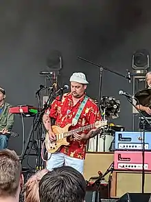 A photo of Isaac Brock in a Hawaiian shirt playing guitar