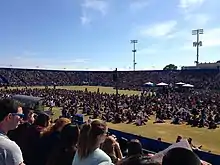 A large crowd of people in an outdoor sports stadium on a clear day