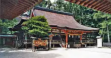 Wooden building with raised floor, vermillion red beams and railed open veranda.