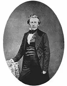 Beardless man with hair combed back, glaring at camera