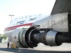 A Pratt & Whitney JT9D museum exhibit with none of the accessories, tubes, wiring and cowls which cover a functional engine. Revealed are the casings bolted together which make up the structural backbone of the engine. The engine thrust is transferred to the aircraft pylon at the top of the turbine case. As this is above the engine centerline where the thrust acts it causes backbone bending in the core engine which in turn causes causes blade tip rubs and performance loss.