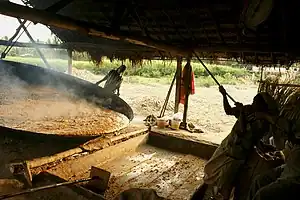 A man tilting a large metal disk to put out the contents