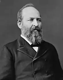 Garfield wears a double breasted suit and has a full beard and receding hairline