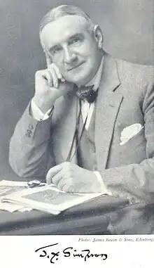 Black and white photograph of James Young Simpson, seated, looking into the camera with papers on a desk in front of him