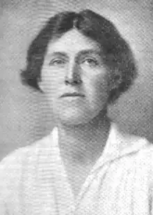 A white woman, her short dark hair centre-parted, wearing a white blouse.