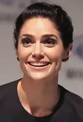 A woman with dark hair is smiling towards the camera.