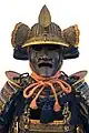 The fukigaeshi can be seen to both sides of the mabizashi (brim), and the shinobi-no-o (cord) secures the mengu (facial armour)