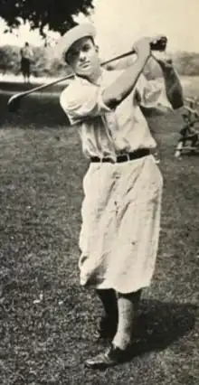 A young white man in a golf swing pose, wearing short loose trousers typical of a 1920s golf costume