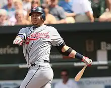 A man in a gray baseball uniform and dark batting helmet