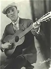 Photograph of Rodgers strumming a guitar