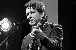 Black-and-white image of Joe Henry playing guitar onstage