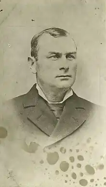 A gentleman posing for a photo in a suit and tie, seen from the chest up