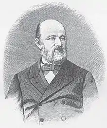 Photograph of Julius Schmidt standing in a suit. He has no hair, but has a dark beard.