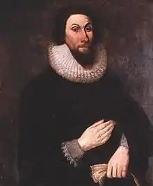 A painting of a man with a stern expression on his face, wearing very dark clothing so that his pale hands show boldly.  His hands are placed in front of him, separately, one above the other.