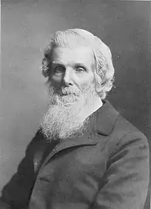 BLack and white portrait of a seated man with long white beard