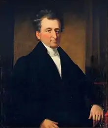 Half-length portrait of sitting Leamy in suit.