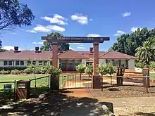 Single storey school building painted in white with red roof tiles.