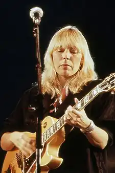 A woman holding her guitar while looking at it