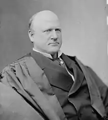 A balding man in his fifties wearing black judicial robes