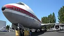 A large airplane with a white-and-gray livery parked on the tarmac.