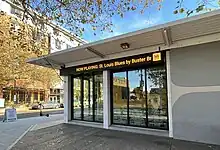 The side of a building with long LED sign near the roof, which includes the yellow KEXP logo and the song title.