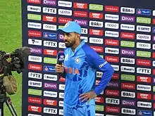 A man in a light blue and black shirt wearing a dark blue cap.