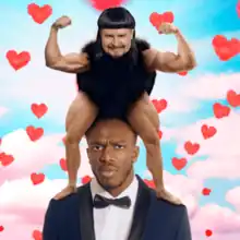 A figure with the head of Oliver Tree, with muscular arms and legs and a squat and hairy body stands on KSI's shoulders, against a sky background filled with love hearts