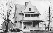 late 19th Century 2-story farmhouse with porches and a barn in the background