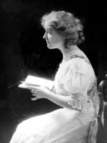 Black and white photograph of Kate Gannett Wells as a young woman. She is pictured in profile, seated and holding an open book.