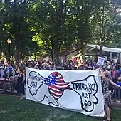 A crowd of protesters hold a sign saying "Immigrants Stay Trump Pence Must Go"