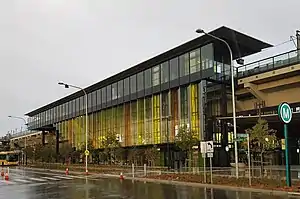 Picture of Kellyville station from the outside. It consists of an elevated platform with a glass façade.