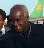 A head-and-shoulders photograph of a black gentleman in a dark suit, looking downwards and to his right.