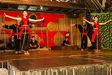 Two pairs of dancers in Kadazan clothing with their arms outstretched.