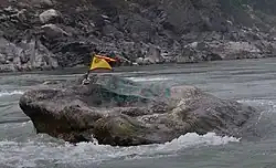 A rock with Kirat flag on top, in the middle of Koshi river