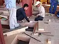 Craftsmen assemble flooring planks in a temple hall