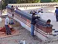 Craftsmen building a tile capped adobe wall