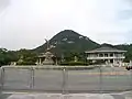 Monument on road in front of the Blue House, administrative building in background