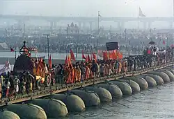 Large group of people and vehicles crossing a pontoon bridge