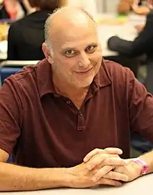 A smiling Caucasian man wearing a red polo shirt.