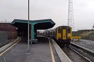 A Train under a train shed roof at a railway station on a dull day.