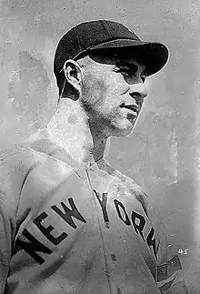 A man in a light baseball uniform and dark cap