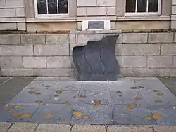 three gray curved stones memorial on sidewalk