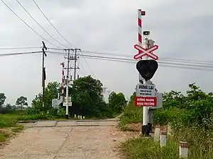 A railroad crossing at Hanoi, Vietnam, with crossing lights, electric bells, and half-barrier gates in their open position